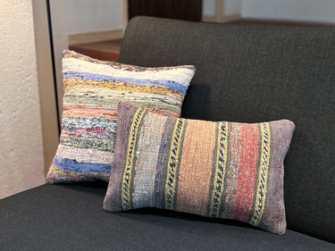 異なるサイズのクッションとソファに置かれた裂き織りキリムクッション（C-13774）の写真