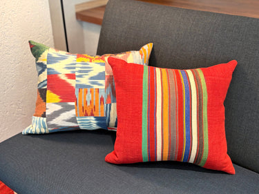 ソファの上に異なるサイズのクッションと置かれたイカットパッチワーク シルククッション(MC-0705)の写真