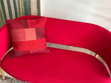 赤のソファの上に置かれる赤のパッチワークのクッションの写真