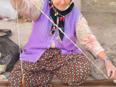 糸をコマで紡ぐおばあさんの写真